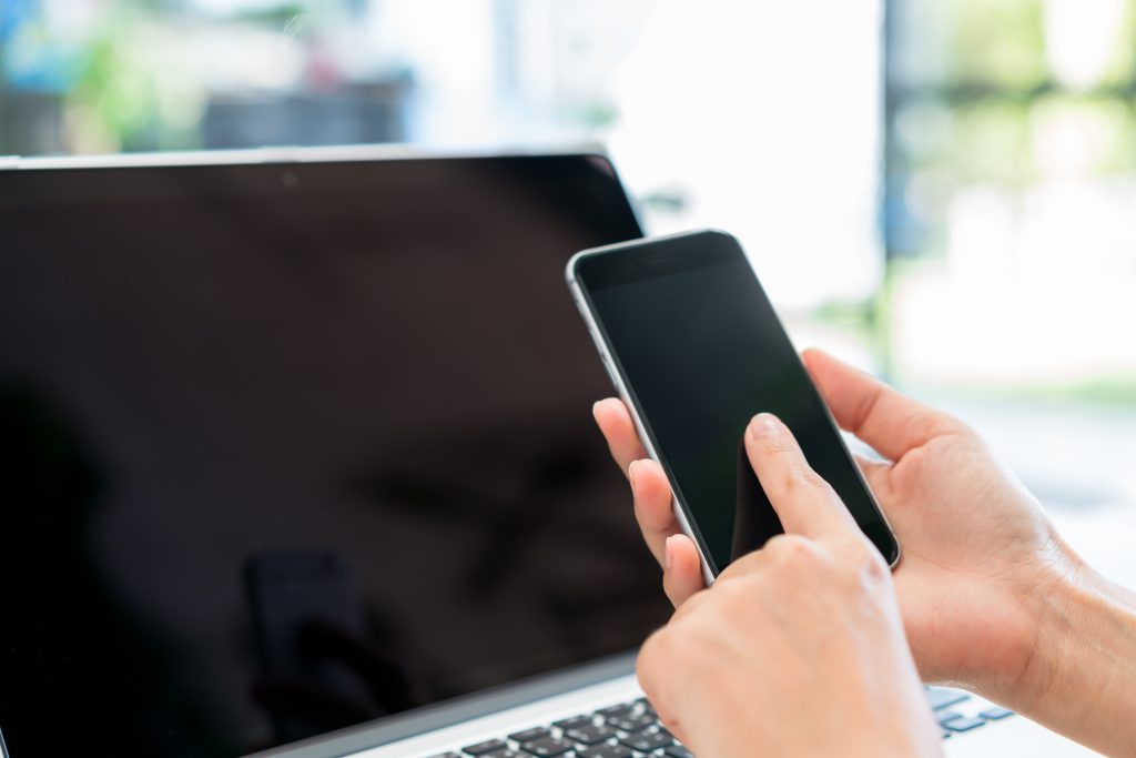 モバイルファーストの基礎知識Closeup of business woman hand typing on laptop keyboard with mobile phone